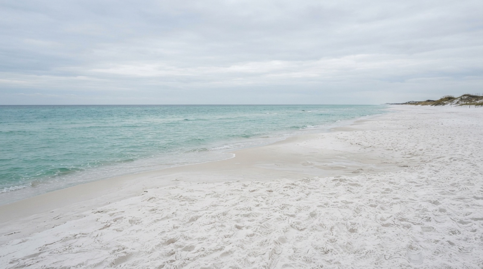 Empty Destin beach stretching toward the horizon under a clear sky.